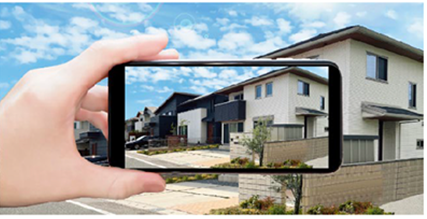 スマートフォンで家の写真を撮影している様子